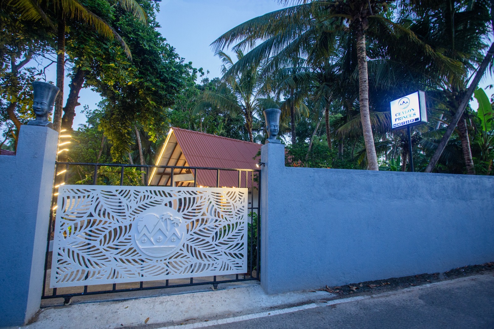 Ceylon Princes entrance gate and illuminated roadside sign among palms