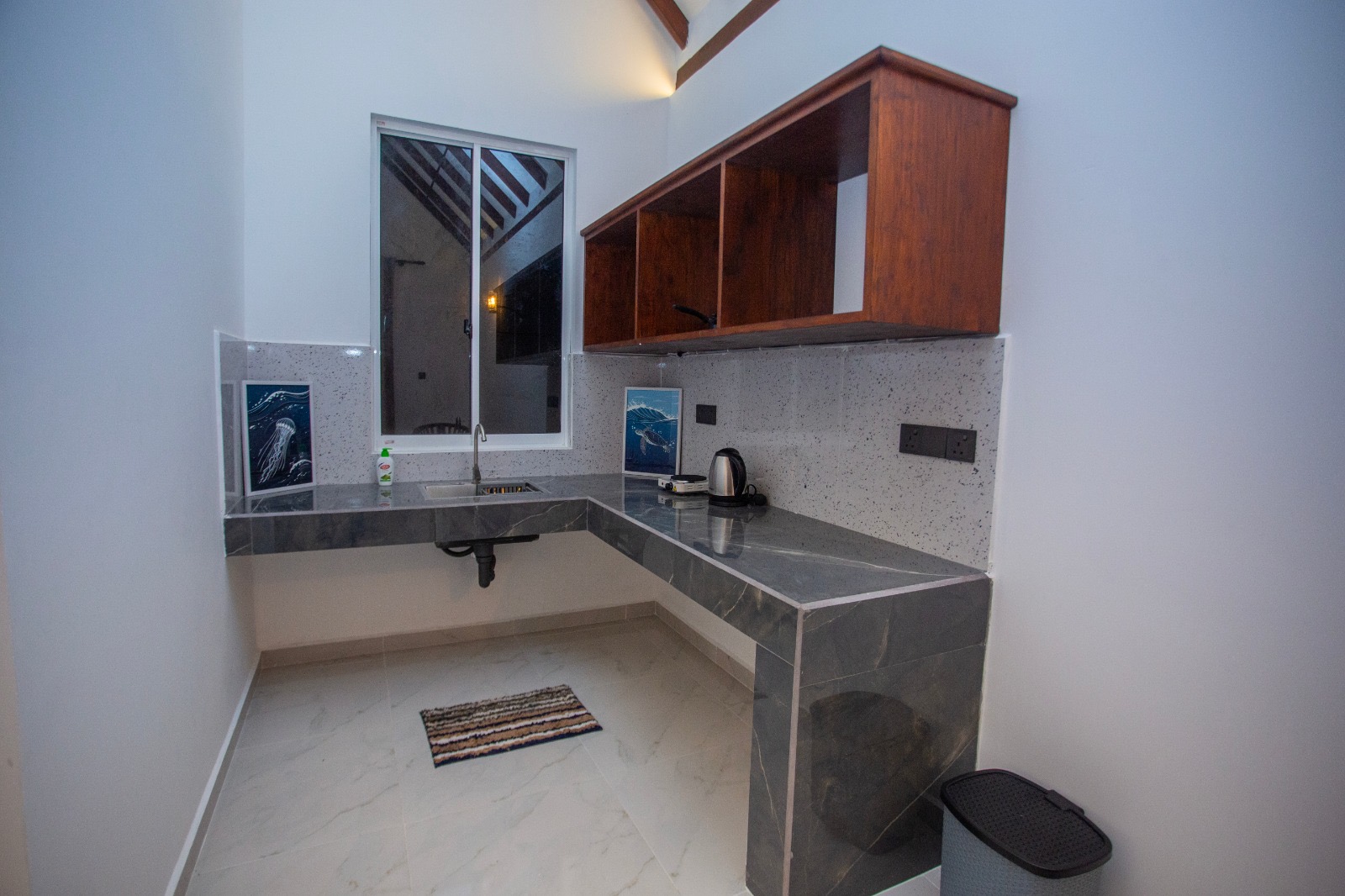 Compact kitchenette with sink, counter, kettle, and timber cabinets