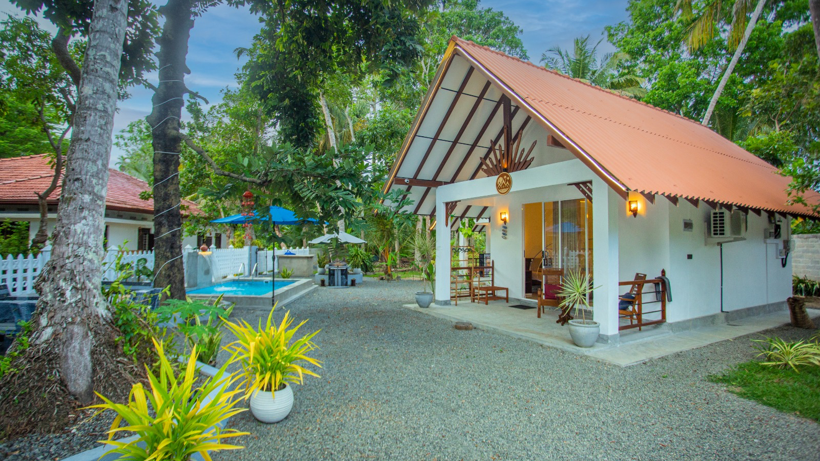 White villa with a pitched terracotta roof in a tropical garden