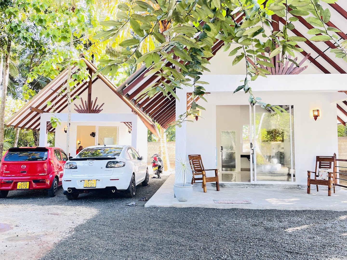 Sunlit white villa frontage beneath tropical trees